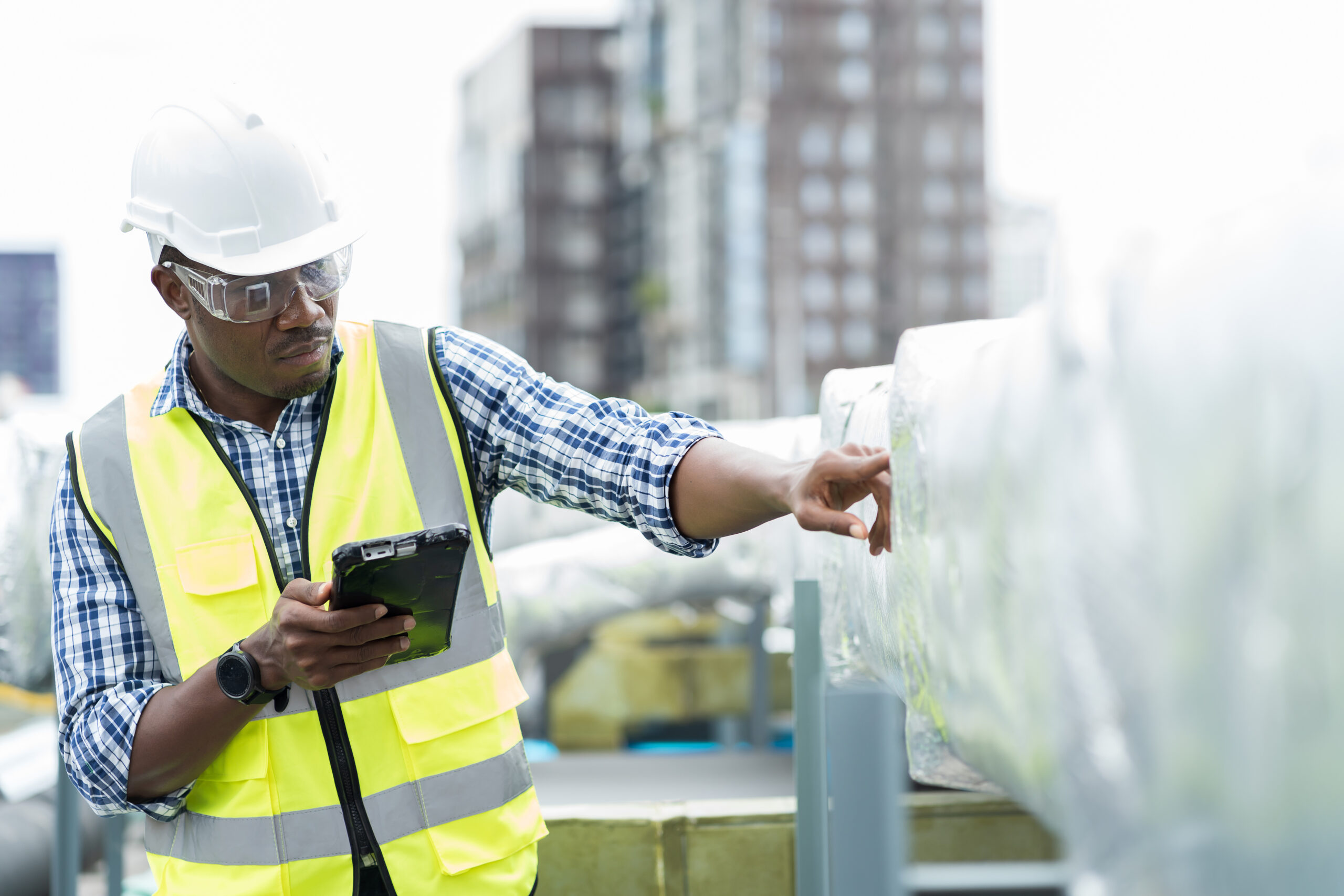 A facilities worker inspects equipment on a roof.